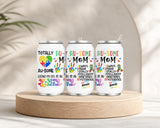 Three white tumblers with colorful puzzle piece designs and text promoting autism awareness, featuring the phrase Proud Au-some Mom Tumbler – Austism Awareness Colorful Puzzle Drinkware, displayed on a wooden platform with a neutral background.
