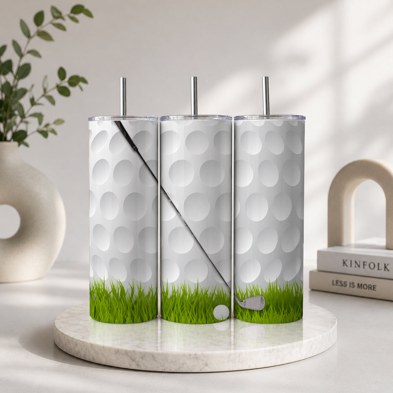 Three Golf 20oz Straight Tumblers arranged side by side, featuring a white golf ball texture with green grass and golf club details, displayed on a marble surface.