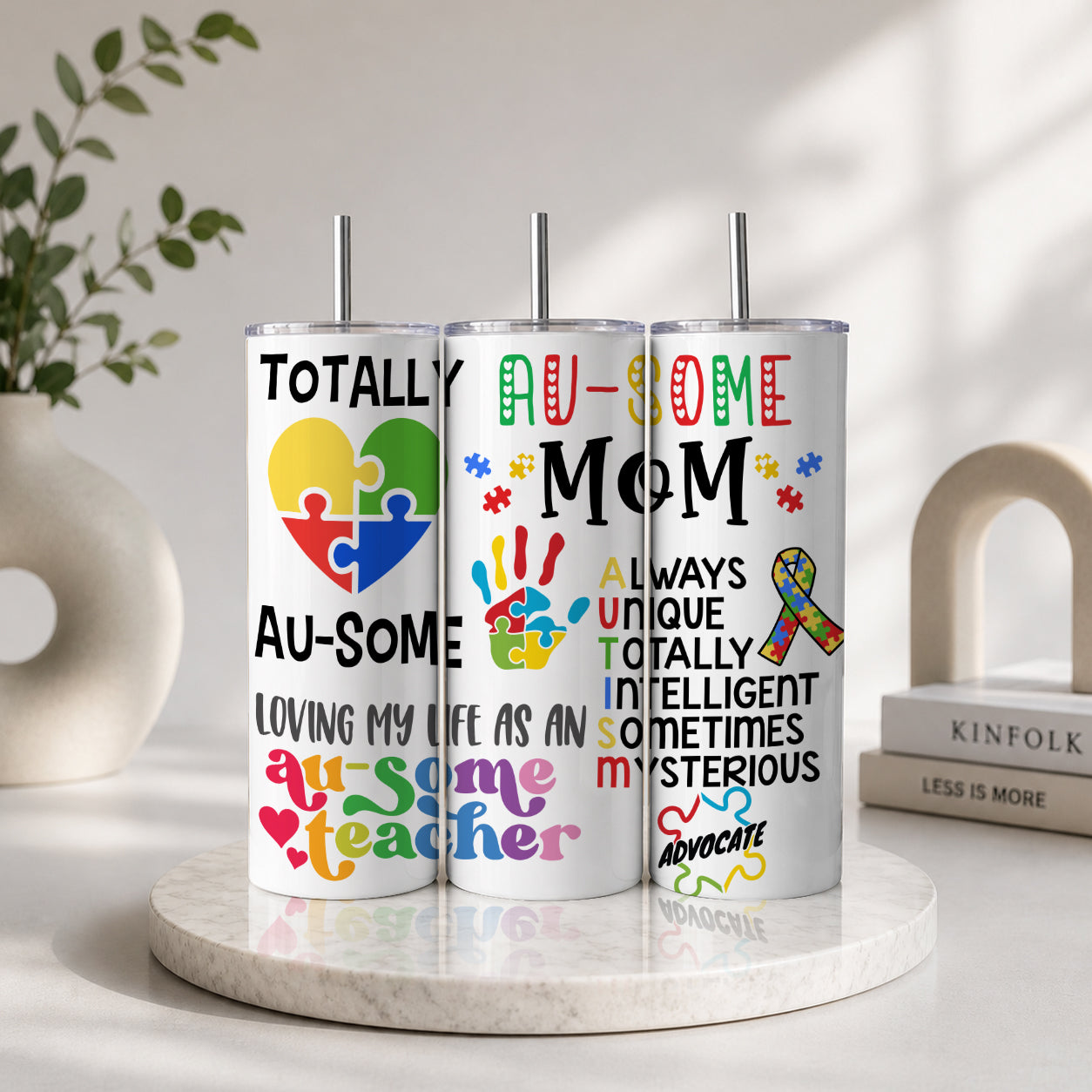 Three vertical stainless steel tumblers with colorful puzzle piece designs and text supporting autism awareness, featuring the phrase Proud Au-some Mom Tumbler – Austism Awareness Colorful Puzzle Drinkware.